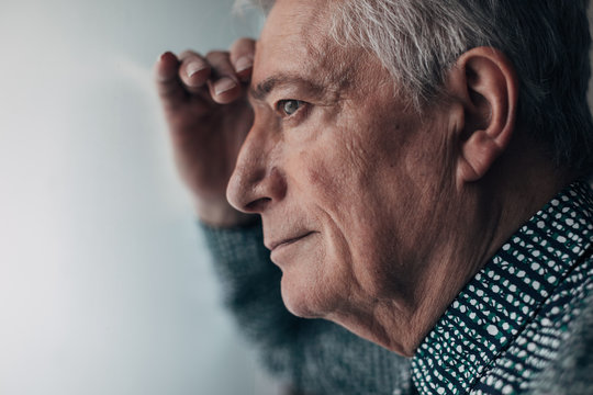 Portrait of an old man looking through the window.