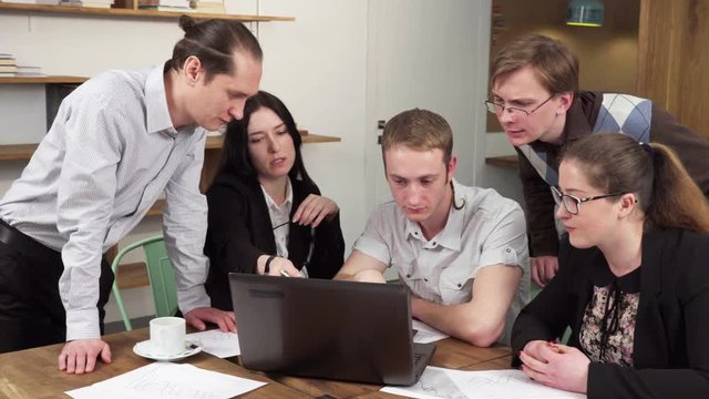Group of business people discussing something looking at laptop screen in the office