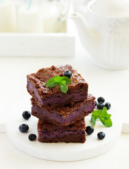 Chocolate brownies with blueberries and cream filling. Dark background.