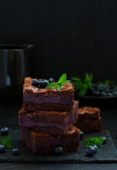 Chocolate brownies with blueberries and cream filling. Dark background.