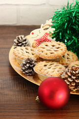 Christmas mince pies on a gold plate with red reindeer on a wood background
