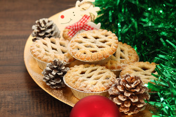 Christmas mince pies on a gold plate with red reindeer on a wood background
