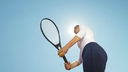 Beautiful young girl tennis player woman serving ball with racket outdoor with sun behind her