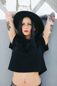 Portrait of a young alternative woman with tattoos standing in the city.