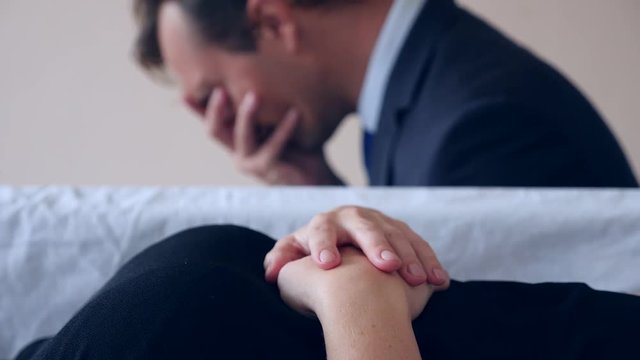 funeral, sadness and mourning concept - a sad man talking and crying next to the coffin. 4k,