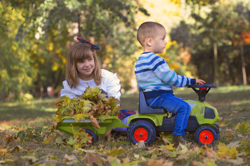 Little boy and girl playing in the park on a beautiful autumn day