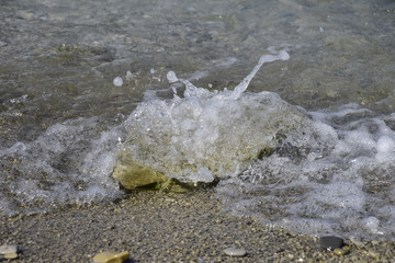 Sea waves run ashore, bubbling and stone covering