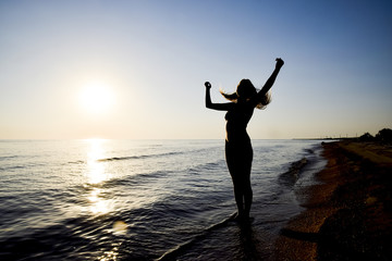 Silhouette of a girl against the sunset by the sea