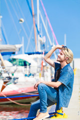 Blonde man sitting near harbor in summer