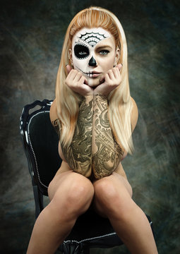Front portrait of a sitting semi nude female with skull makeup and tattoos . 3d rendering