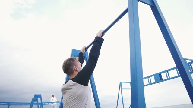 Young man doing parkour tricks on the beach near the sea
