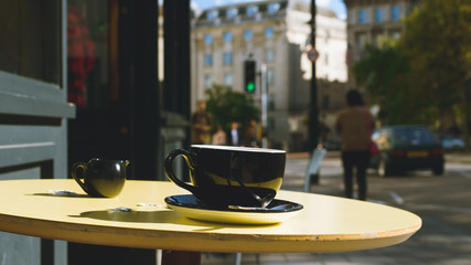 Black Cup And Saucer With Milk Jug On A Street Cafe Table A