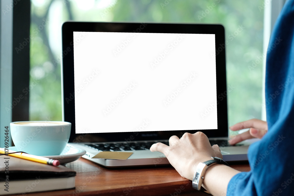 Wall mural woman hands typing laptop computer with blank screen for mock up while sitting by the window, techno