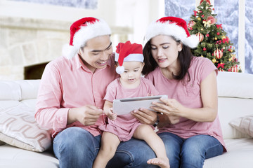 Young family with tablet and Santa hat