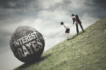 Workers pull a stone with Interest Rates text