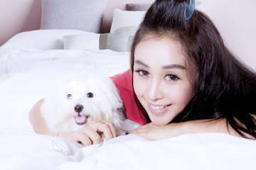 Pretty woman with cute dog on bed