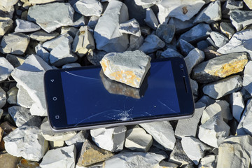 Frustrated phone on the rocks. Glass shattered on rocks on a sma