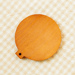 Blank wooden coaster on check pattern fabric background
