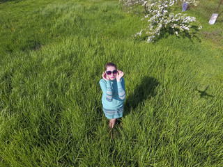 Fototapeta premium Young girl in a light green dress on the lawn with green grass.