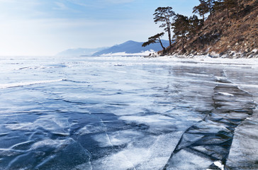 Winter shore of Lake Baikal with frozen cracks on ice
