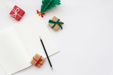 white opened notebook paper and pencil with presents and Christmas tree, copy space