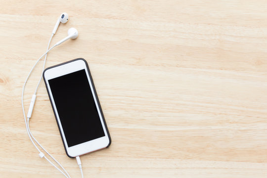 Smart Phone And Ear Phone On Wood Table