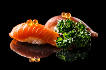 Closeup composition of two fresh salmon sashimi sushi with caviar and parsley on a dark background