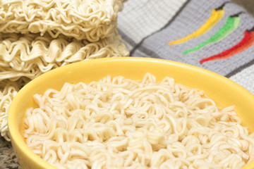 Instant Noodles in Yellow Bowl, with Raw Noodles, on Dark Marble Background