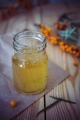 Honey in a glass jar and a branch of sea-buckthorn