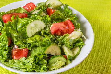 Fresh salad. Tomato, cucumber and greens in white bowl