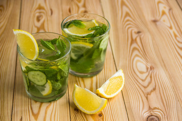 Detox water, fresh organic lemonade with ice, cucumber, lemon and mint on wooden background