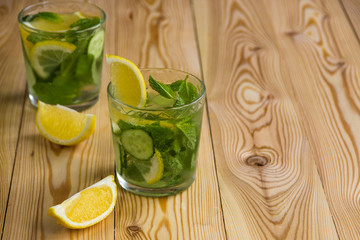 Detox water, fresh organic lemonade with ice, cucumber, lemon and mint on wooden background