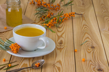 Tea with sea-buckthorn orange berries in a cup and organic honey