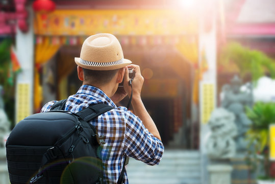 Tourist sightseeing old town, travel concept.Street photographer taking a picture of old shrine chinese temple in phuket old town with vintage camera ,rear view and lens flare effect.