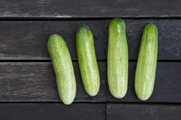 Fresh green cucumber on dark wood background