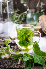 Mint tea in a glass, grass on a wooden table