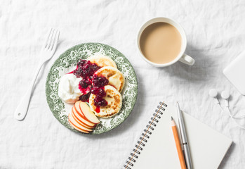 Cottage cheese pancakes with greek yogurt and cranberry sauce, coffee with milk, notebook, phone...