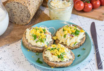 egg spread on round fresh homemade bread, decorated with spring onion and crushed yolk