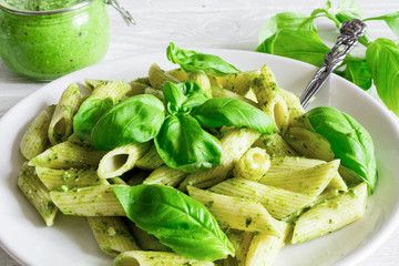 penne pasta with basil pesto and herbs in a plate with fork
