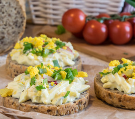 egg spread on round fresh homemade bread, decorated with spring onion and crushed yolk