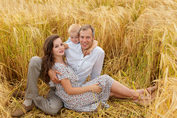 Family sitting on the grass in a wheat field