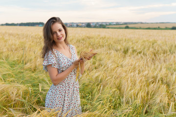 Young woman in dress holds wheat ears in hands