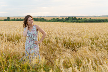 Fototapeta na wymiar Beautiful woman in dress on a wheat field