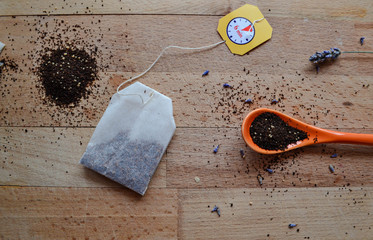 Tea bag, tea granules in the orange spoon on wooden background