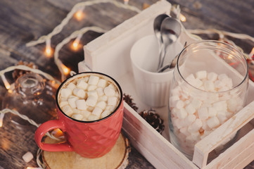 Obraz na płótnie Canvas hot cocoa with marshmallows on wooden table with christmas lights. Cozy winter home concept