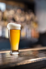 Glass of light beer on a dark pub