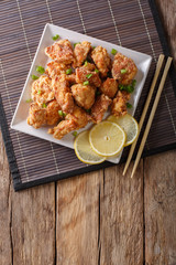 Spicy chicken karaage with lemon and green onion close-up. Vertical top view