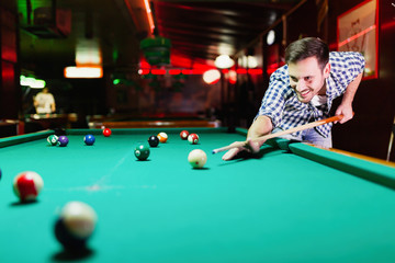 Hansome man playing pool in bar alone