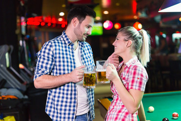 Happy couple drinking beer and playing snooker