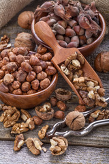 Hazelnuts and walnuts on a spoon and in a linen sack on an old wooden table